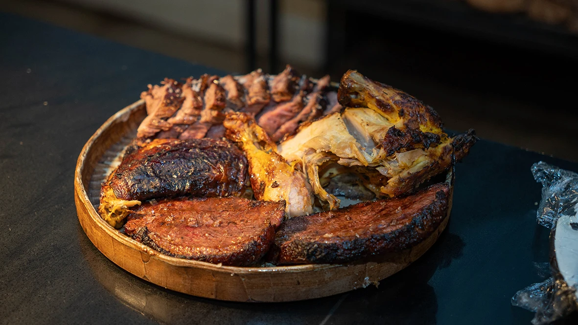 Wood-fired beef and chicken served together on a wooden board
